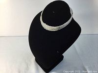 Triple row milky Lucite bead choker displayed on black bust background, showing necklace shape and bead detail.