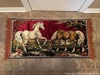 Photo of rectangular plush velvet tapestry featuring two horses and floral elements on a red background, measuring approximately 38x19 inches.