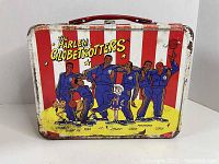 Front view of 1971 Harlem Globetrotters metal lunch box showing cartoon team illustration with wear and rust on edges and surface