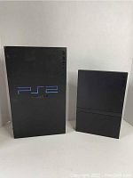 Front view of Sony PlayStation 2 box beside the slim PS2 console.