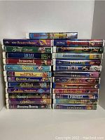 Photo showing 25 Walt Disney VHS tapes in two stacks with titles including Beauty and the Beast, Pinocchio, Fantasia, and others.