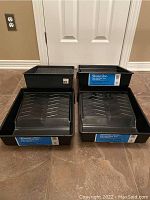 Four black plastic paint trays on floor, showing overall condition and quantity.
