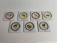 Seven Humpty Dumpty collectible dog coins from the 1960s in protective holders, showing different dog breeds and labeled with breed names.