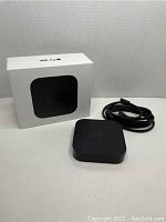 Apple TV 3rd generation device with power cable and box displayed against white background.