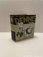 Front and side view of Dennis The Menace book with dust jacket showing cartoon image and title