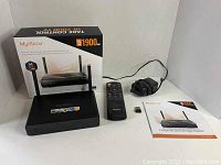 Photo of the MyGica ATV 1900 Pro Android TV box, remote, power adapter, USB dongle, user manual, and product box on a white background