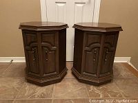 Pair of tall hexagonal wooden side tables placed side by side on tiled floor against a wall.