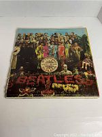 Front cover of Sgt. Pepper's Lonely Hearts Club Band vinyl showing iconic artwork, with edge wear and discoloration.