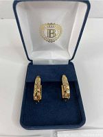 Pair of gold plated hoop earrings displayed upright in blue velvet Bradford Exchange box showing brand logo on interior lid.