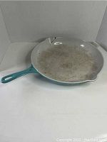 Top and handle view shows the white enamel interior with wear and teal handle.