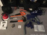 Photo showing all items in lot including power polisher, hand vacuum, saws, hatchets, locks, keys, and manuals.