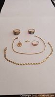 Overview of seven gold jewelry pieces on white background