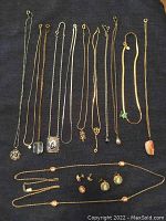 Twelve necklaces and cameo earrings laid out on dark fabric