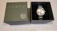 Box with Nic & Syd branding and Swarovski certification sticker, alongside watch in black interior box insert.