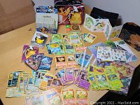 Overview of trading cards, binders, stickers, coins and lunchbox tin arranged on table