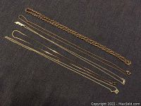 Full view of all five necklaces laid out on dark fabric showing condition and length.