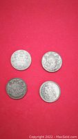 Four silver Canadian 50 cent coins displayed on red background showing both obverse and reverse sides.