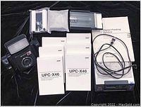 Photo showing Sony DKC-C300X camera, 6 UPC-X46 printing paper packs, new laminating paper, cables, and manual