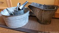 Set showing galvanized steel tub with scuttle bucket, watering can inside tub, and cowbell inside tub