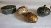 Four paper mache trinket boxes of various shapes and designs, showing overall lot contents.