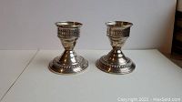 Pair of weighted sterling silver candlesticks with round bases and ornate detailing.