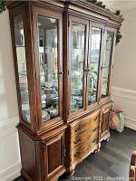 Full view of traditional two-piece mahogany china cabinet showing glass display shelves, cabinet doors, drawers, and decorative woodwork.