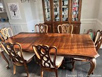 Dining room setup showing extendable mahogany table with leaf inserted and six matching chairs