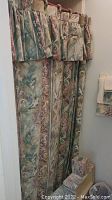 Full view of floral fabric shower curtain with matching valance in bathroom.