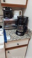 Black & Decker convection oven, coffee maker, waffle maker, and electric kettle arranged on kitchen counter.