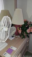 Photo showing 20 inch Duracraft fan, smaller 12 inch Advantage fan, 24 inch side table lamp and silk floral arrangement in basket on dresser.
