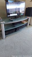 Entertainment stand holding flat-screen TV, VHS players on shelves below