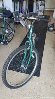 Front angled view showing green frame, front tire, handlebars, and brake cables.