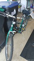 Full view of the green Huffy Superia mountain bike with gel tech seat and handlebars showing brake cables and mounted air pump.