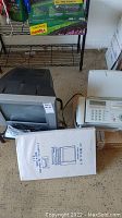 CRT television and fax machine with user manual on floor