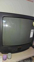 Front view of black Sharp 20-inch CRT television showing screen and control buttons with a label on the upper right corner.