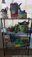 Photo of black 4-shelf wire rack holding garden and pet supplies including watering can, pots, basket with tools, bottles of pest control products, and supplies boxed in Vigoro no-dig edging.