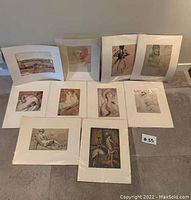 Full group of ten unframed prints and drawings laid out on floor with some standing against wall.
