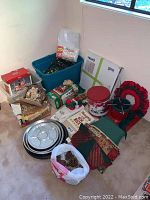Wide-angle view of assorted Christmas decor including lights, linens, wreath, tins, and boxes