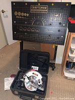 Craftsman work table with measurement graphics and circular saw in carrying case on floor.