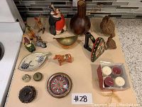 Full view of all 17 pieces arranged on kitchen countertop showing variety of painted iron figurines, wooden vase, ceramic dish, candle set, and small decorative pieces.