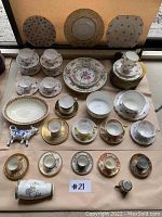 Overview of all assorted china cups, saucers, plates, bowls and decorative pieces laid out on brown paper