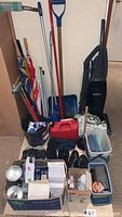 Photo showing overall lot contents including cleaning tools, umbrellas, shoes, vacuum, and household supplies