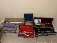 Casio keyboard in box, multiple instrument cases and metal stands on floor