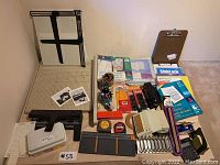 Wide view showing large paper slicer, letter paper cutter, stationery items including pens, tape, measuring tapes, stapler, paper punch, paper sleeves, filing sorter and clipboard.