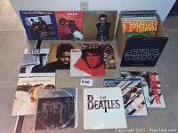 Top-down view of multiple LPs arranged on floor showing front-row album covers and boxed set at right