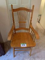 Front view of oak wooden armchair showing contoured seat, spindle backrest and armrests.