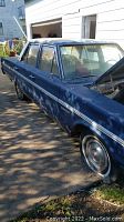 Photo of dark blue vintage Plymouth 4 door sedan parked outside house, showing passenger side and body condition.