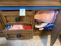Drawer with assorted folded fabric linens including tablecloths and cloth pieces in varied colors.