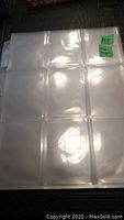Clear plastic trading card page showing nine pockets for trading cards in a 3x3 layout.