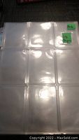 Photo showing clear plastic trading card page with 9 pockets and handwritten note indicating 18 pages.